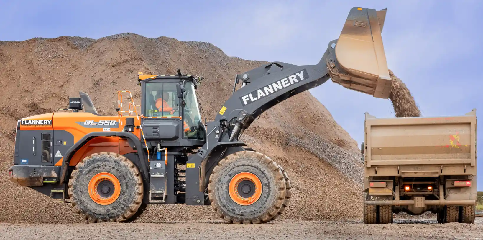 Front loading shovel loading stone into a lorry.