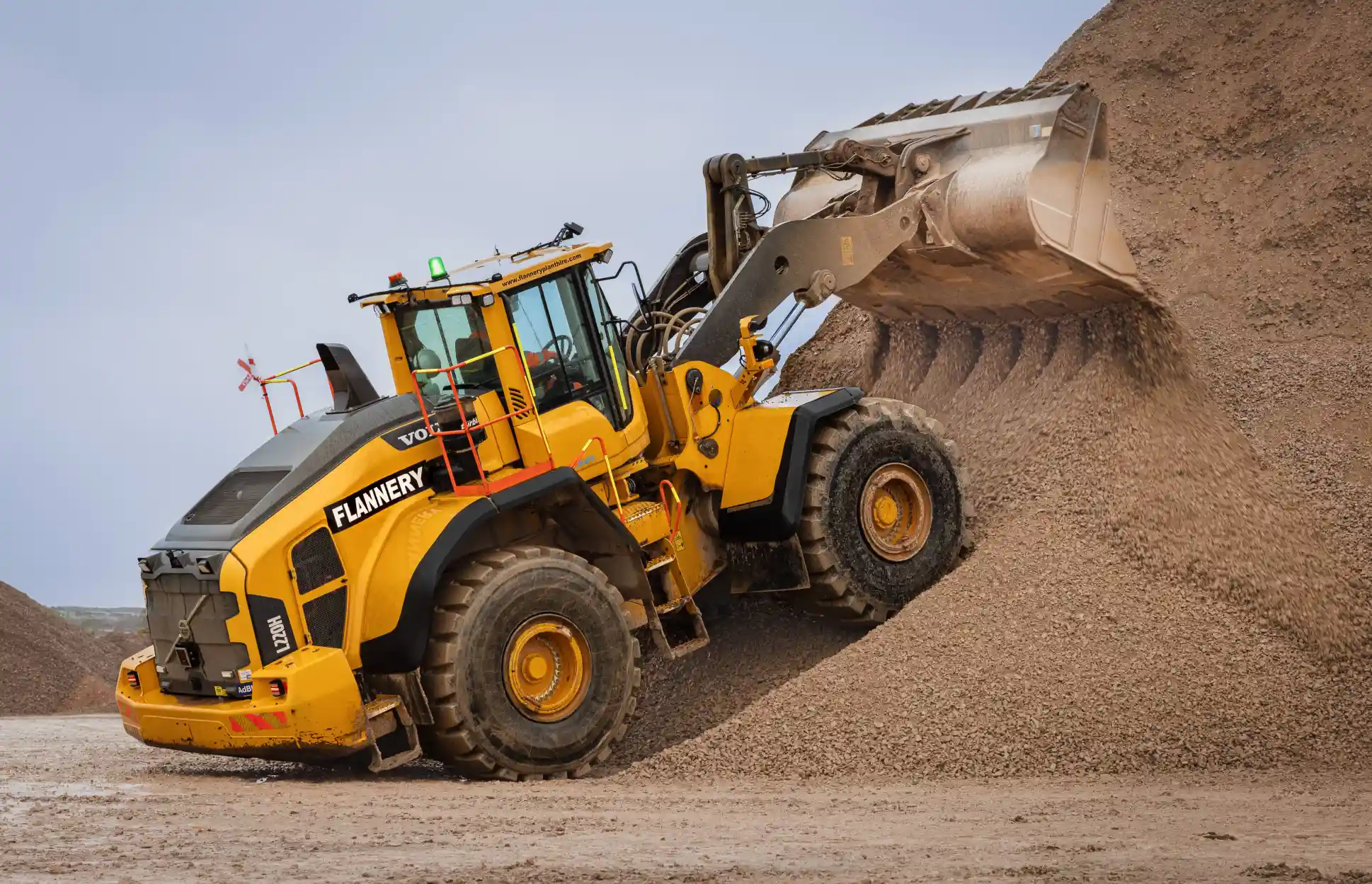 Front loading shovel pushing stone on a quarry site.